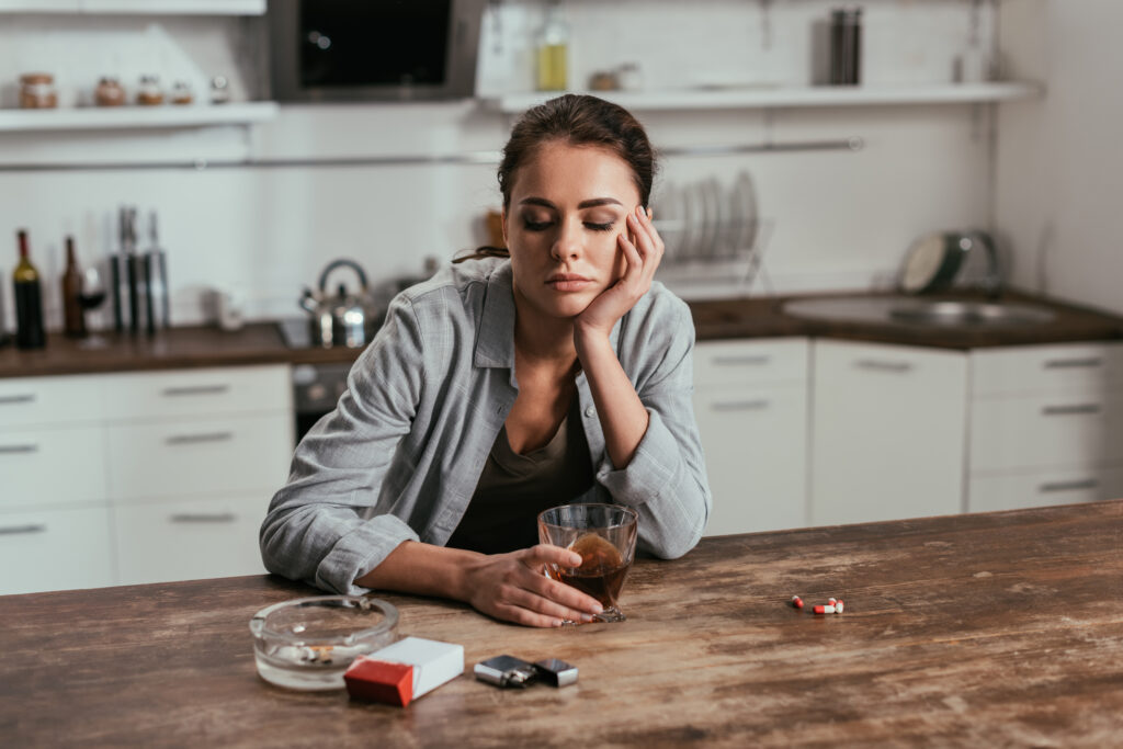 worried woman holding whiskey glass beside cigaret 2023 11 27 05 08 18 utc Early signs of addiction in women Early signs of addiction in women,spotting addiction signs,women's addiction symptoms