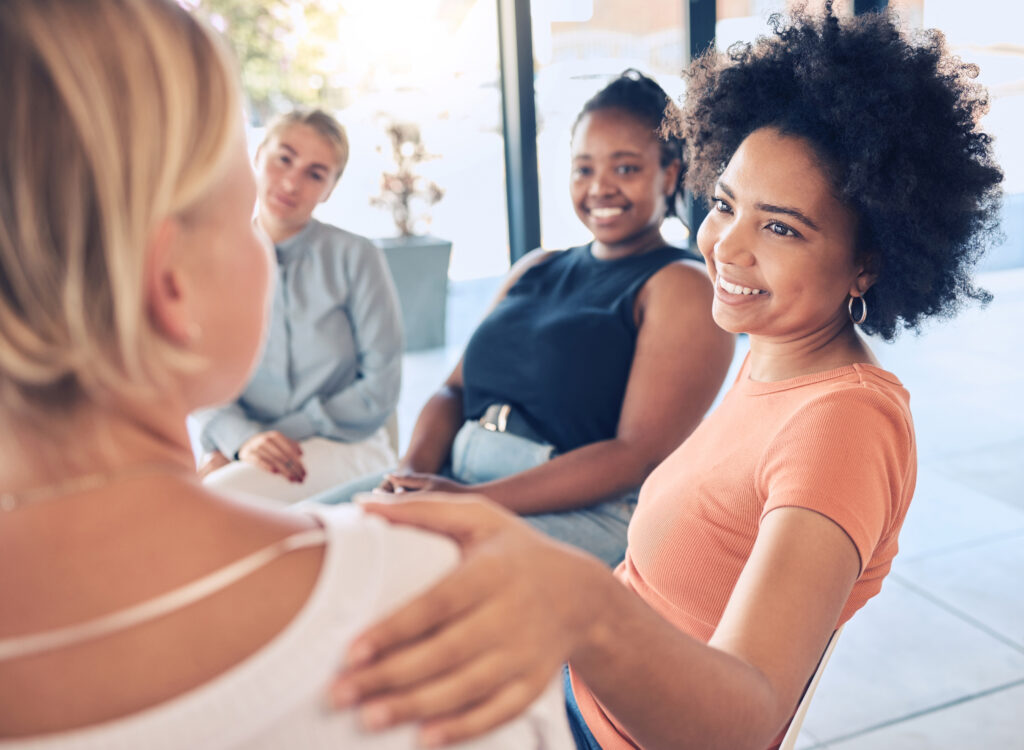 A group of women sitting together in a circle during a therapy session, sharing their experiences and offering support.