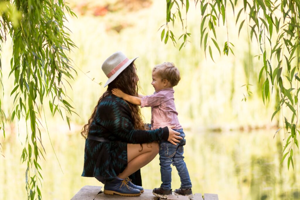 A mother squats down to her son’s level, smiling and making eye contact, symbolizing the balance between motherhood and recovery.