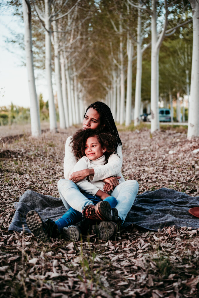 A mother in recovery sitting outside, holding her son close, as they both relax together.