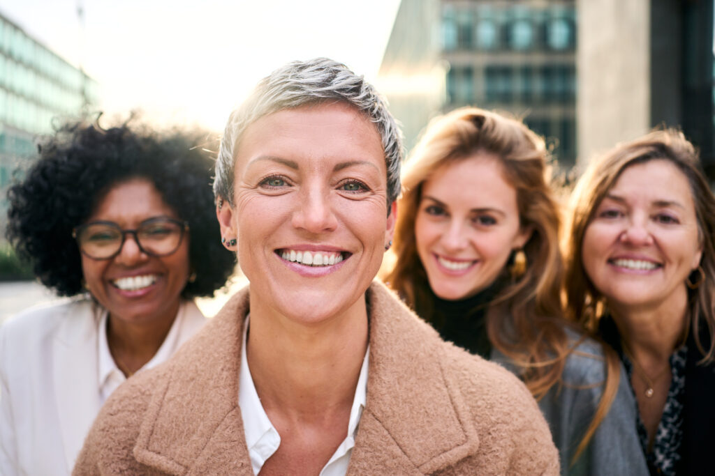 A group of women in a workplace setting, discussing how to overcome barriers to mental health treatment while balancing professional responsibilities.